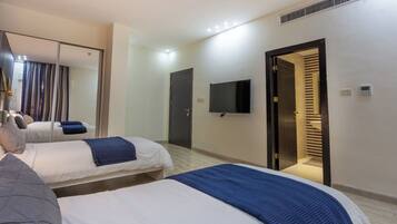 A hotel room with two beds, a flat-screen TV, a mirror, and a door leading to a bathroom.
