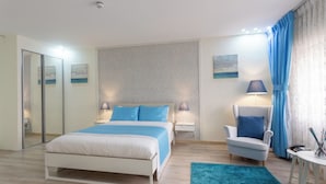 A modern bedroom with a bed, bedside tables, a chair, a desk, and a mirror. - ALBASEM Hotel Apartments (Amman)