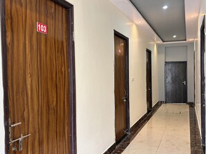 Un pasillo con puertas de madera, numeradas 103, y piso de baldosas.
