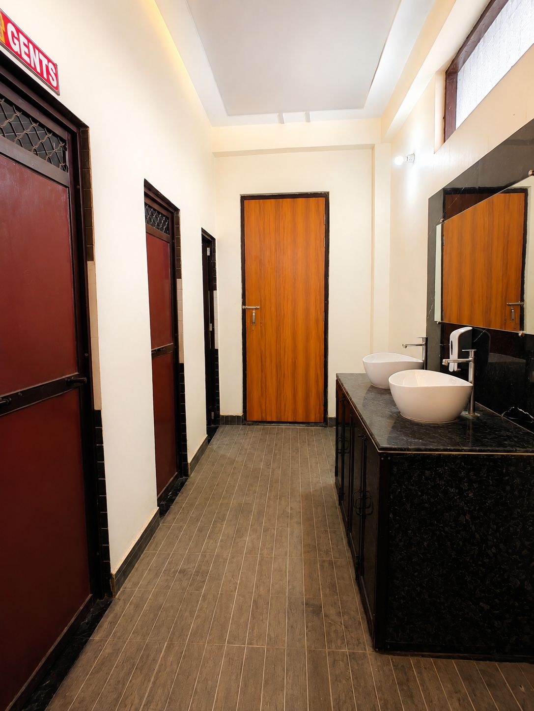 A hotel bathroom with a wooden door, a sink, and a mirror.