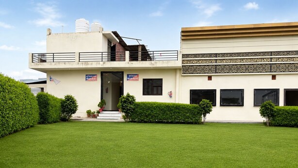 A two-story building with a flat roof, a balcony on the upper floor, and a gated entrance. - Madhuvan Resort (Kanpur)