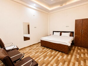 Habitación de hotel con cama, espejo, armario y una zona de estar con sillas.