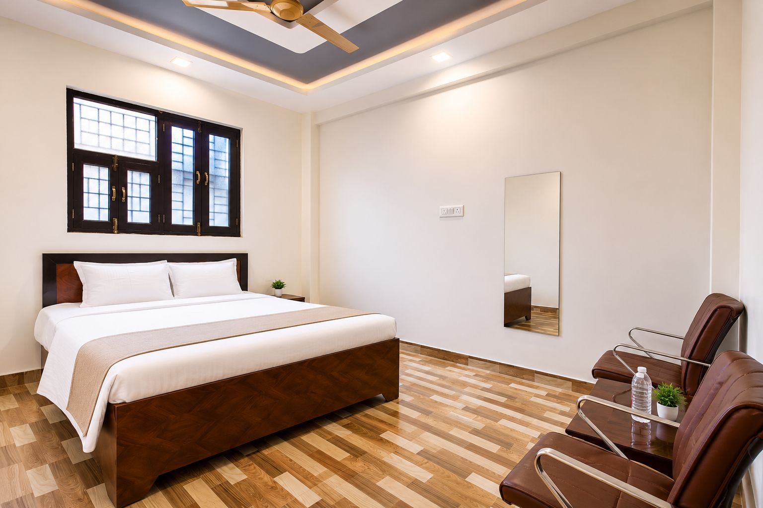 A hotel room with a bed, a chair, a mirror, and a window with blinds.