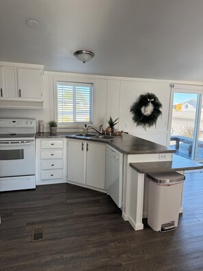A kitchen with white cabinets, a stainless steel sink, and a built-in dishwasher. - Cozy Beach Place Cottage 3-bedroom house with AC in charming Desert Aire (Mattawa)
