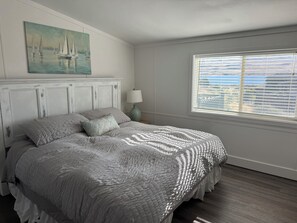A bedroom with a bed, a painting, a window with blinds, and a lamp. - Cozy Beach Place Cottage 3-bedroom house with AC in charming Desert Aire (Mattawa)