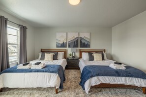 Ein Hotelzimmer mit zwei Betten, einem Fenster mit Vorhängen und einer Wand mit drei Bildern.