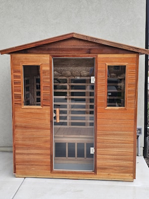 Ein hölzernes Gebäude mit geneigtem Dach, einer zentralen Tür mit Glasfeldern und zwei Seitenfenstern.