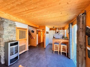 A wooden interior with a stone wall, a fireplace, and a kitchen area with stools. - Cabin in Annaberg With Swimming Pool (Annaberg-Lungoetz)