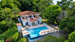 A two-story house with a swimming pool, surrounded by lush greenery. - Casa Promesa  Infinity Pool & Ocean Views (First Bight)