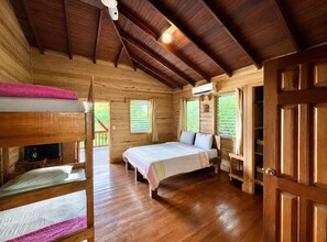 A wooden cabin with bunk beds, a single bed, and a wooden door. - Casa Promesa  Infinity Pool & Ocean Views (First Bight)
