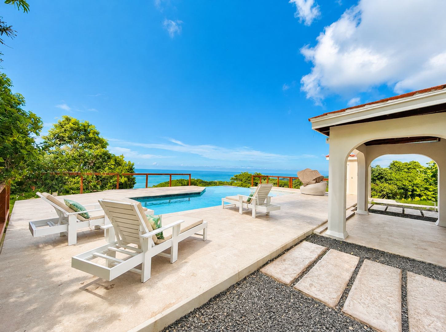 A poolside area with lounge chairs and a view of the ocean.