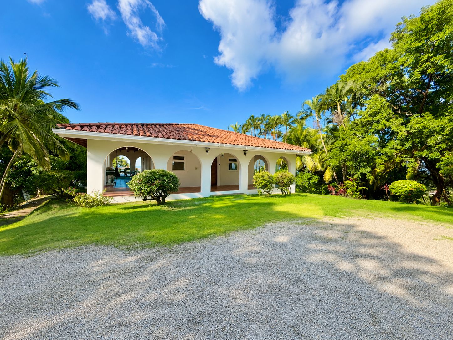 A two-story building with a red-tiled roof, arched windows, and a covered patio area.