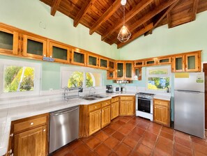 A kitchen with wooden cabinets, a stainless steel dishwasher, a gas stove, and a refrigerator. - Casa Promesa  Infinity Pool & Ocean Views (First Bight)