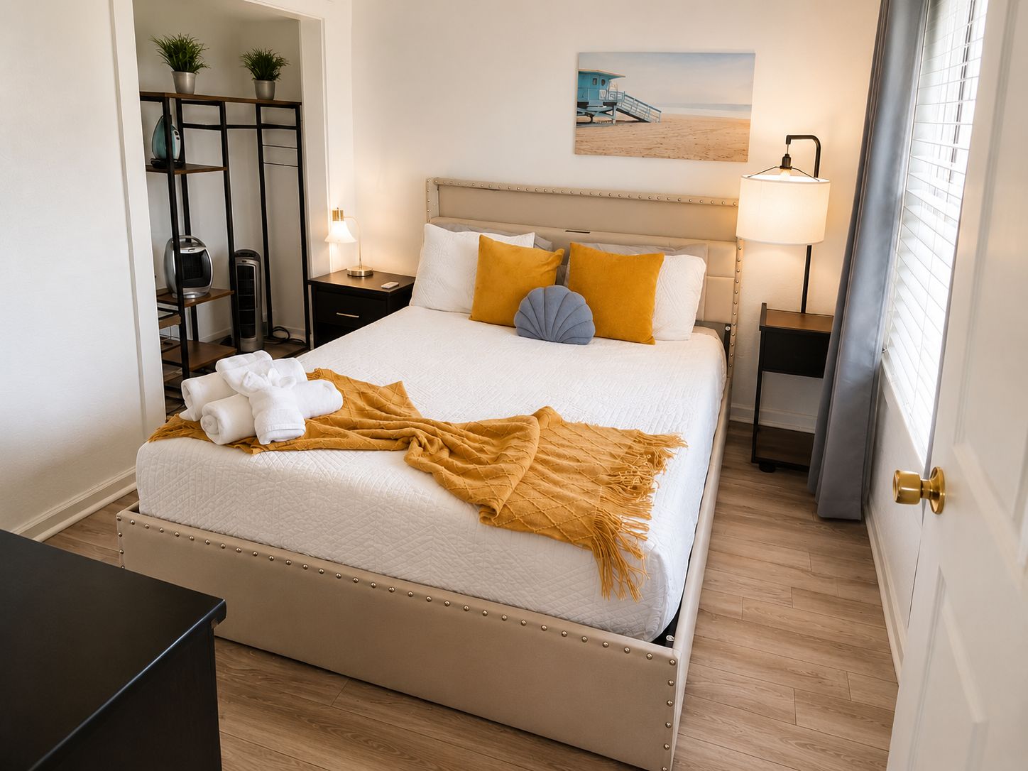 Una cama bien hecha con cabecera, una mesita de noche con lámpara, y una estantería con plantas.