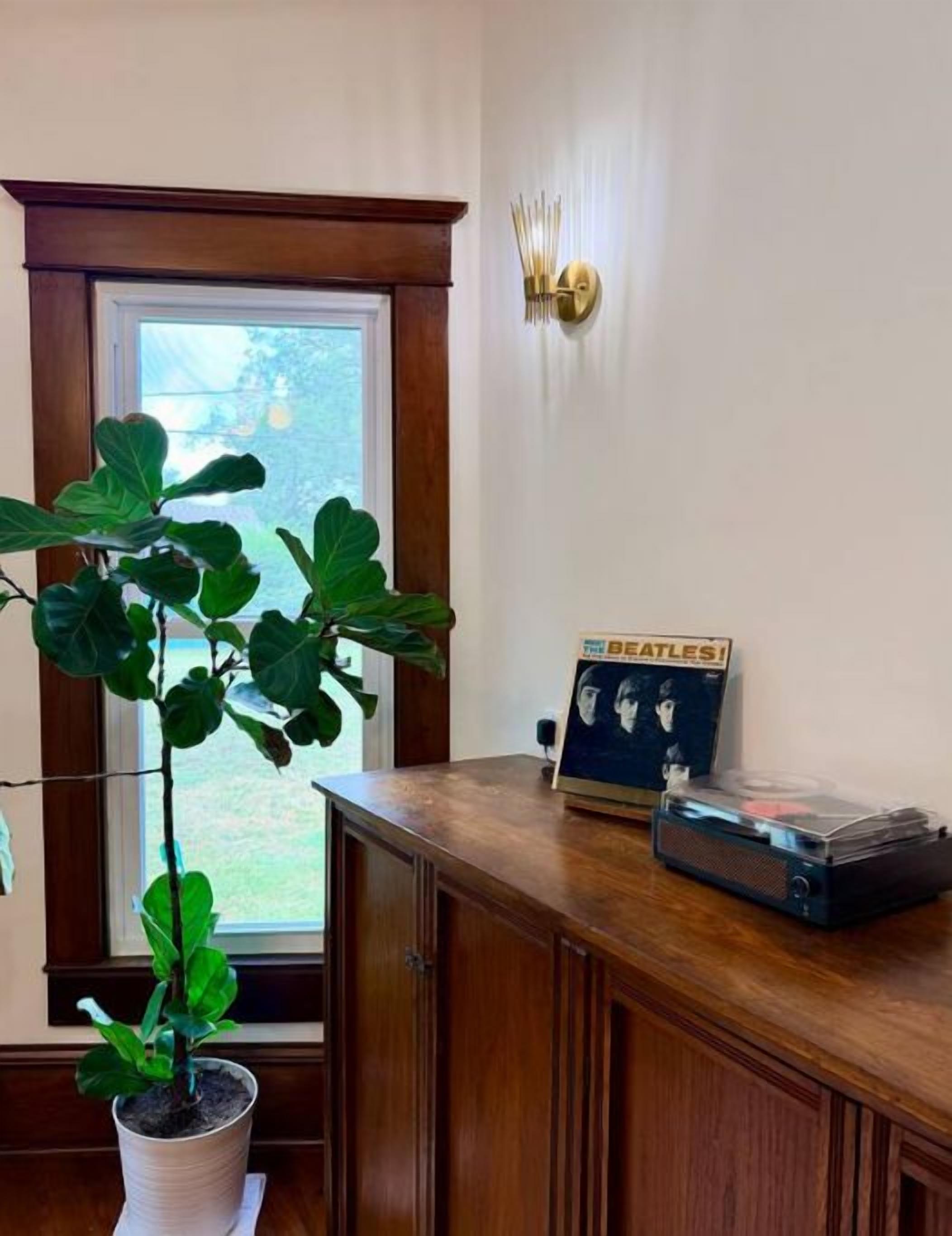 Quarto com armário de madeira, planta em vaso, quadro e luminária na parede.