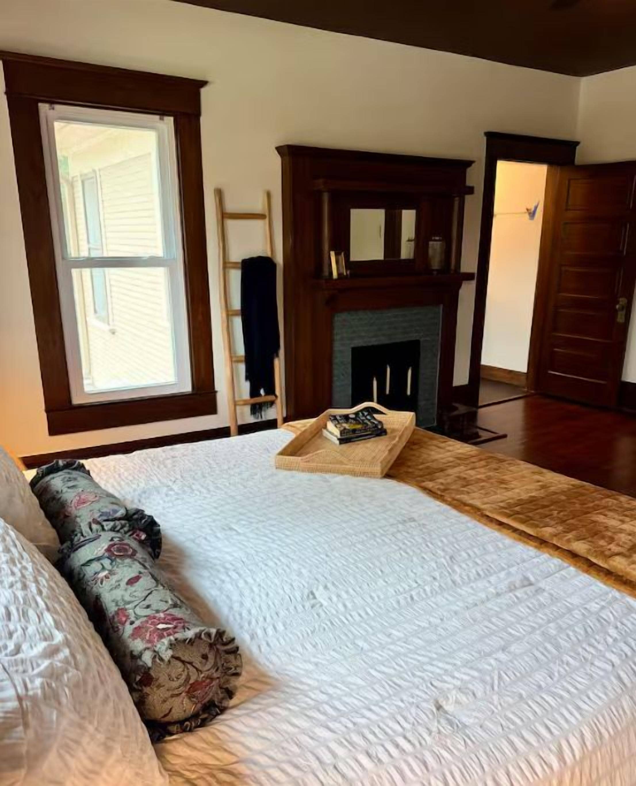 Ein Schlafzimmer mit Bett, Kamin, Fenster und Tür.