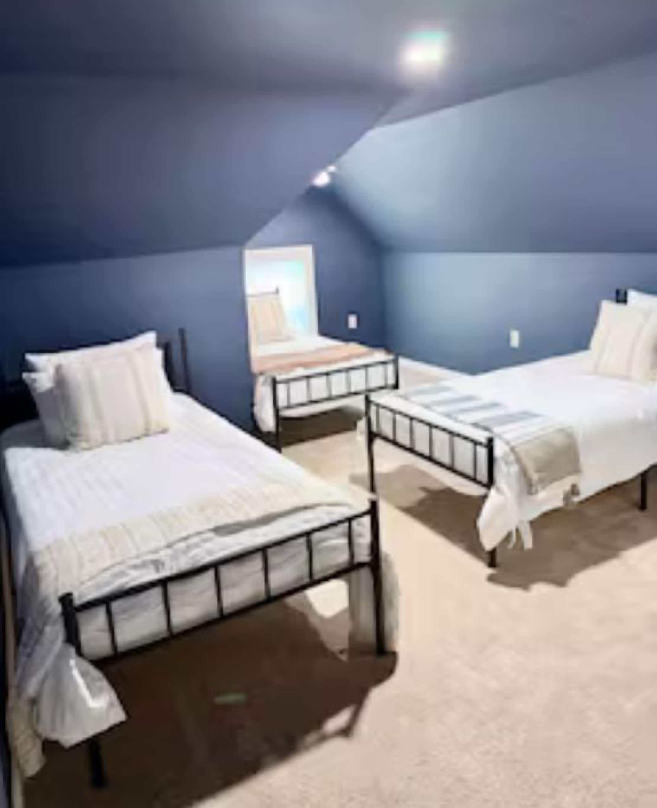 A room with two beds, a window, and a ceiling light.