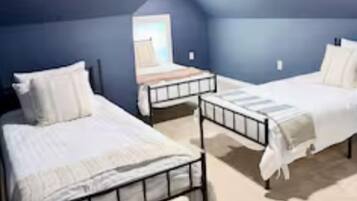 A room with two beds, a window, and a ceiling light.