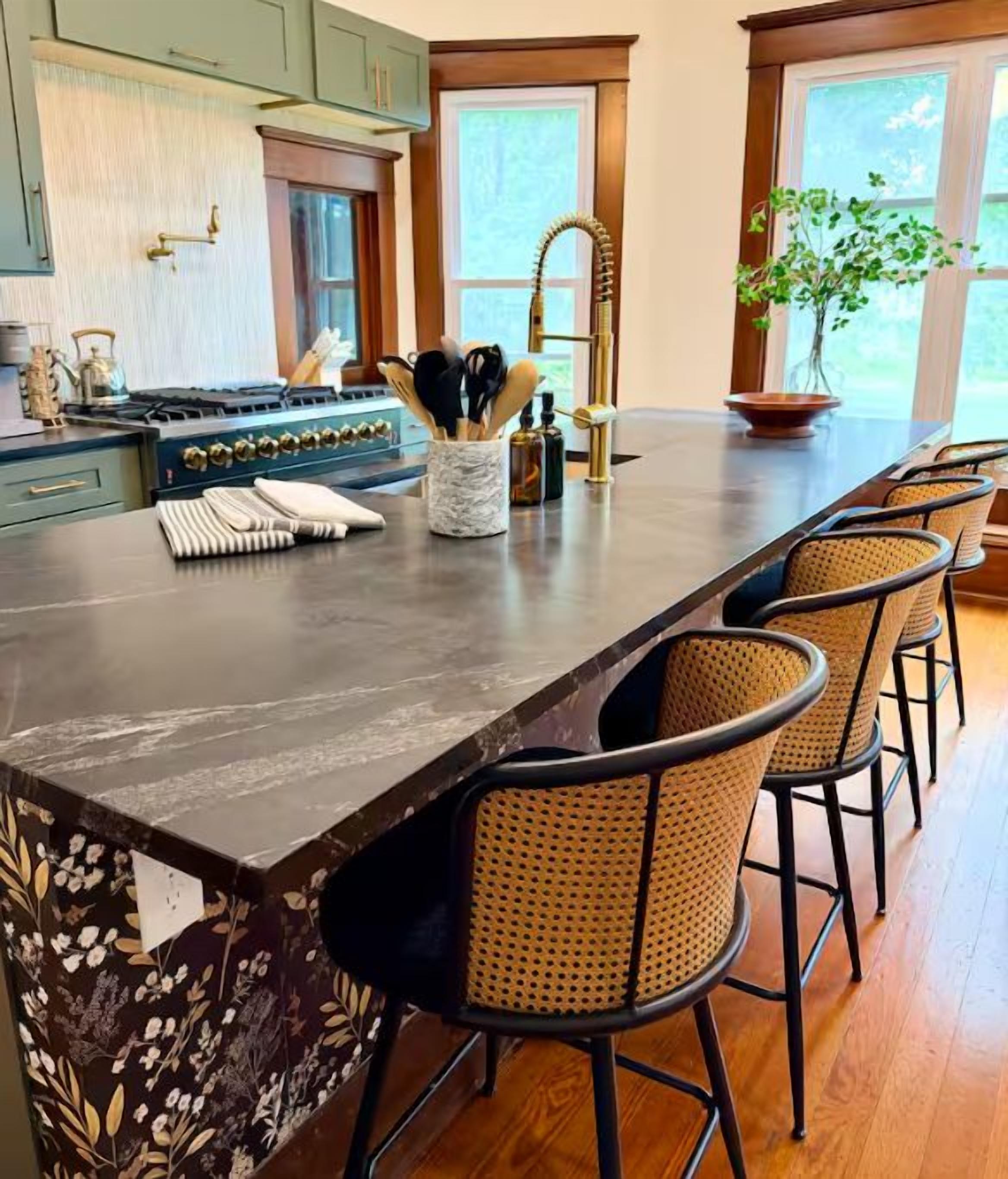 A kitchen with a long island, bar stools, and a stove.