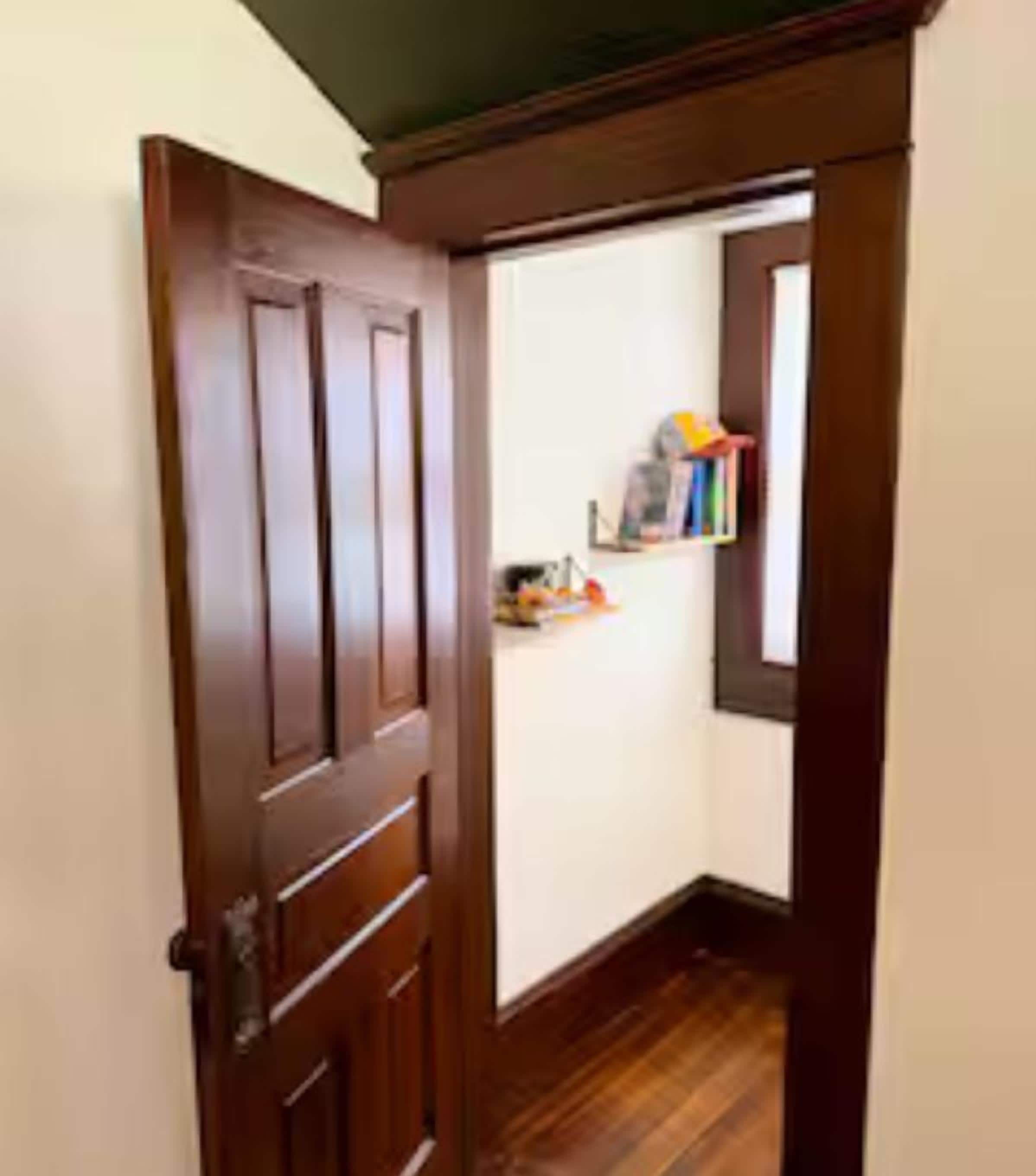 A wooden door leading to a hallway with a wooden floor.