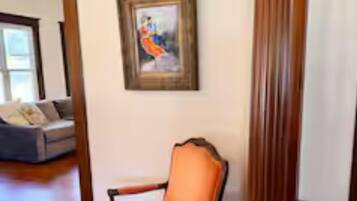 A room with a wooden chair, a framed painting, and a tall column.