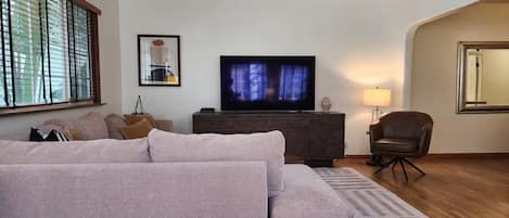 A living room with a sofa, a television, a lamp, and a mirror.