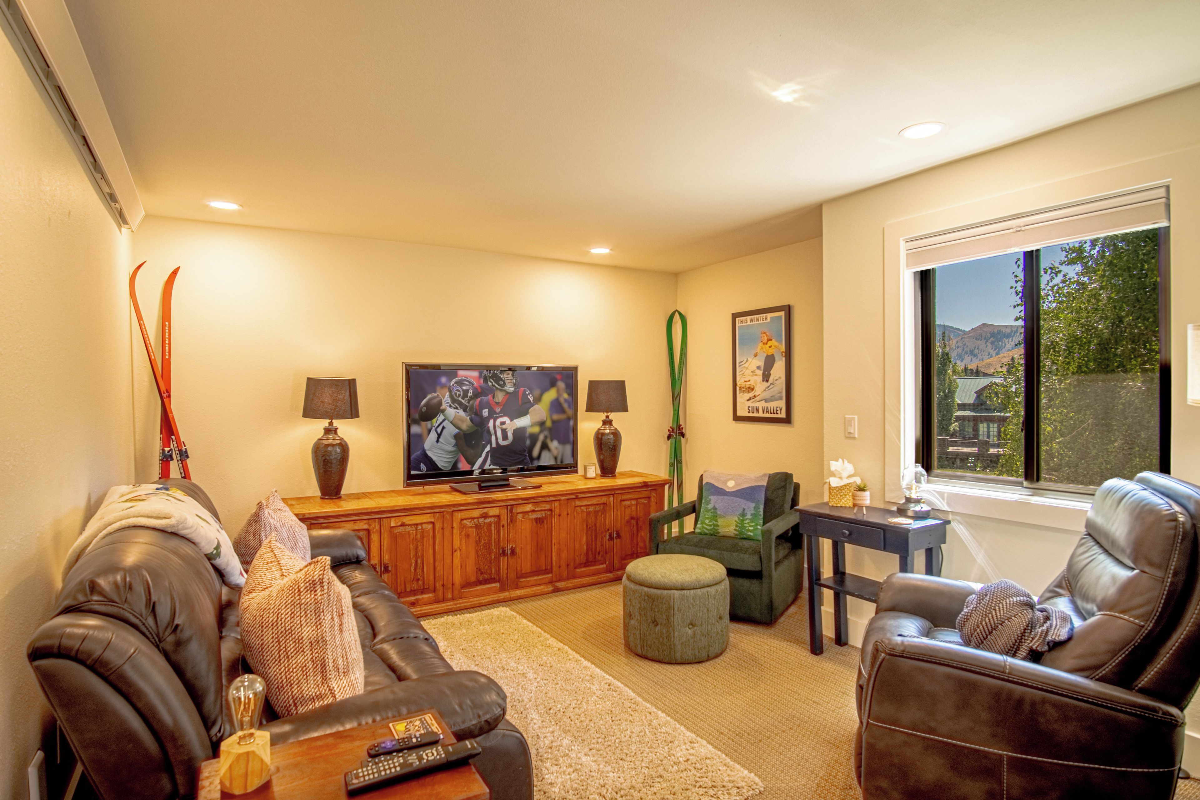 A living room with a television, a sofa, a coffee table, and a window with a view.