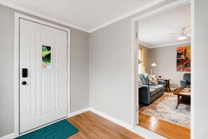 A hallway leading to a living room with a sofa and a table. - 2 Bed, 1 Bath Cozy Ranch, Large Kitchen, Garage (Clawson)