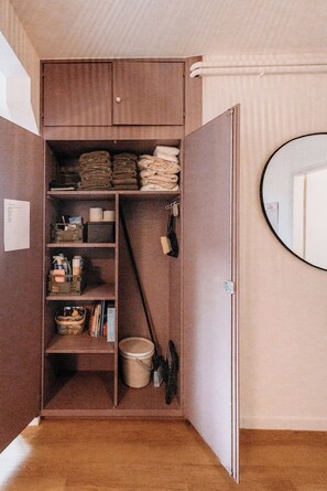 A compact storage unit with shelves, a hanging rack, and a door. - Casa 2 – Modern Vacation Rental on Lake Maggiore (Vairano)