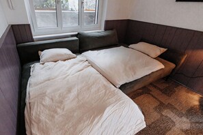 Een kamer met een bed, een raam en een bruine muur.