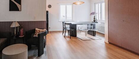A modern living room with a sofa, a coffee table, and a dining area with chairs and a table.