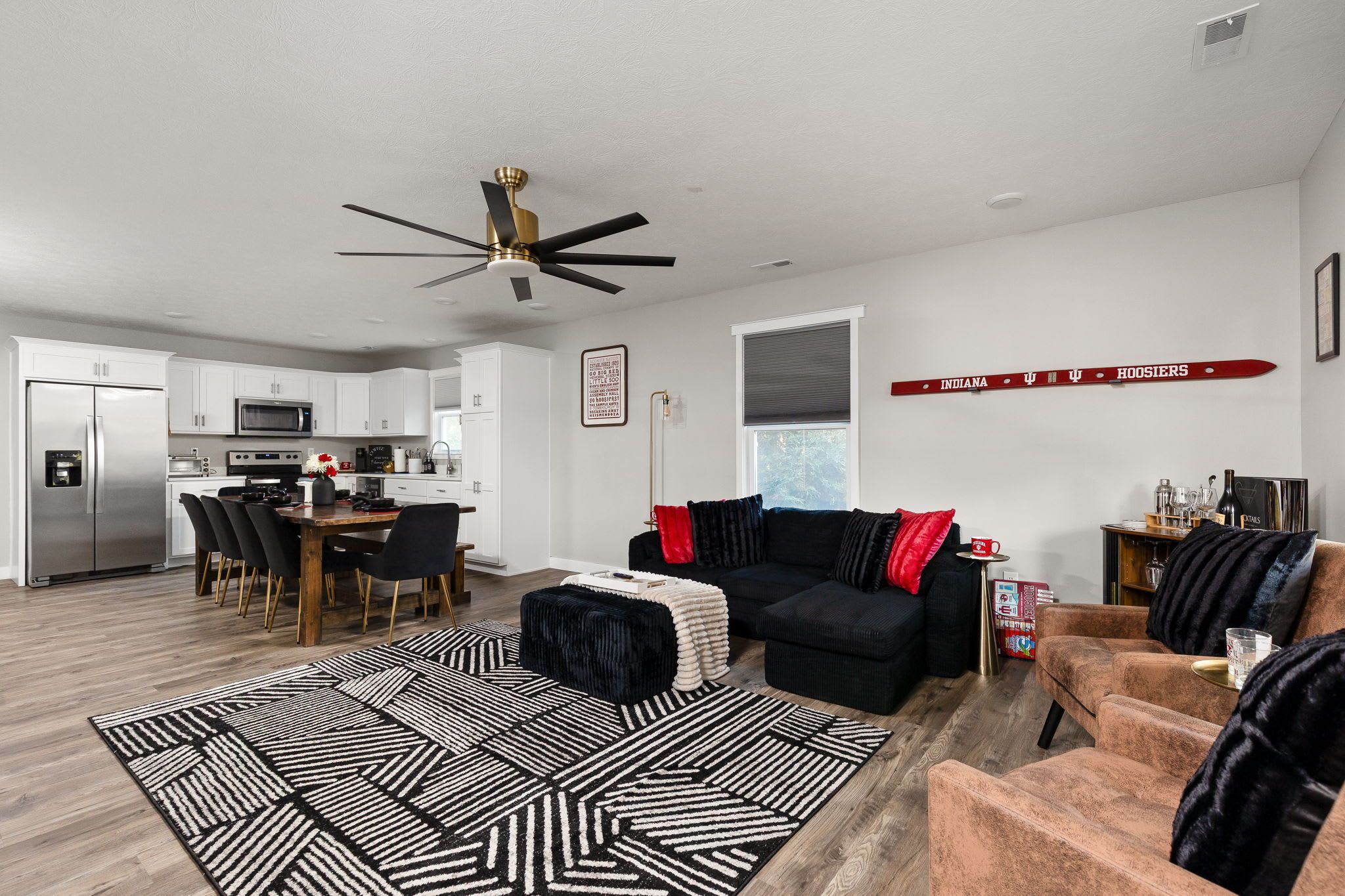 A modern living room with a black sofa, a coffee table, and a dining area with a wooden table and chairs.
