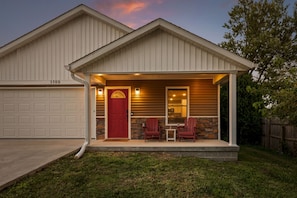 A residential house with a garage, a red door, and a porch with two chairs and a table. - Hoosier Hideaway | King Bed, Beer Pong, Shotski (Bloomington)