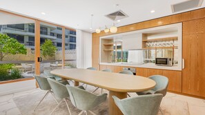 A modern kitchen with a central island, wooden cabinetry, and a view of a balcony with outdoor furniture. - Sol 601 - Coolangatta/ Kirra Luxury Apartment - Min. 3 Night Stays - Linen Provided (Coolangatta)