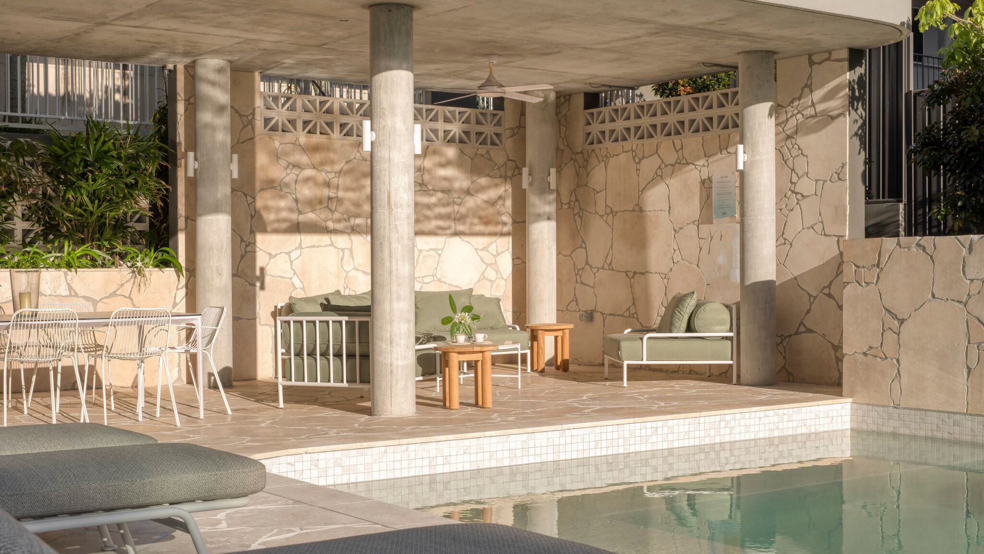 Area piscina con zona relax, tavolo e ventilatore a soffitto.