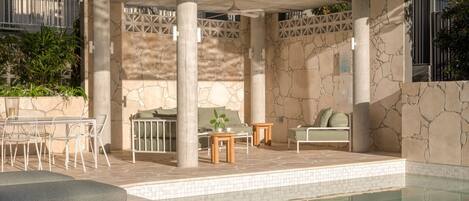 Area piscina con zona relax, tavolo e ventilatore a soffitto.