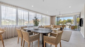 A spacious room with a dining area, a sofa set, and a large window with curtains. - Sol 601 - Coolangatta/ Kirra Luxury Apartment - Min. 3 Night Stays - Linen Provided (Coolangatta)