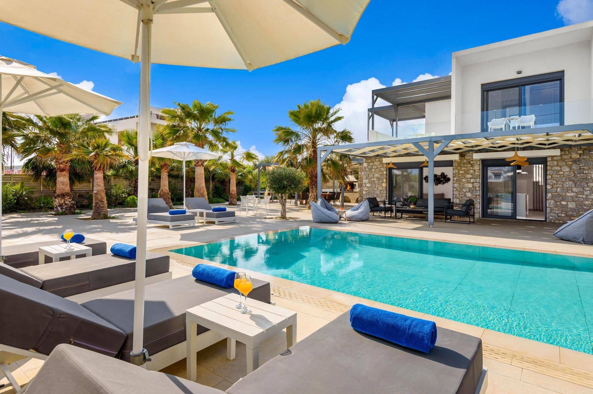 Un espace piscine moderne avec des chaises longues, des parasols et une piscine à l’eau d’un bleu cristallin.