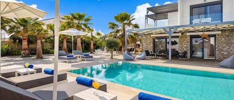 Ein moderner Poolbereich mit Liegestühlen, Sonnenschirmen und einem klaren, blauen Pool.