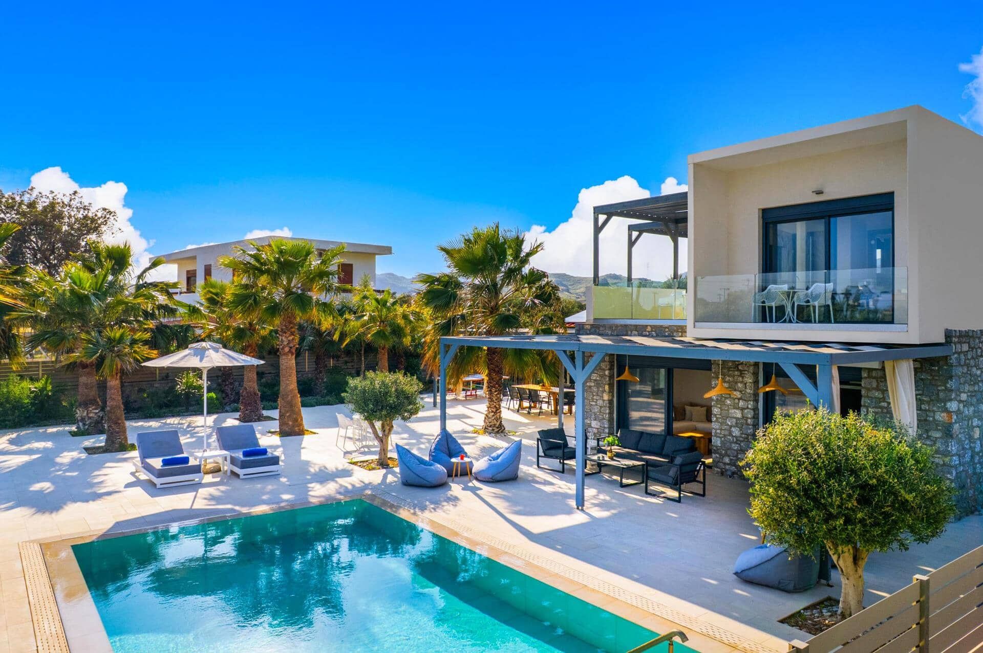Ein moderner Außenpoolbereich mit Liegestühlen, einem Pool und einem zweistöckigen Gebäude mit Balkon.