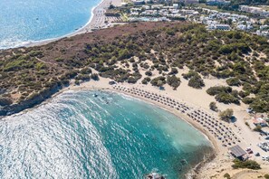 An aerial view of a coastal area with a sandy beach, a marina, and a cluster of buildings. - Villa Artemis Lindian Palm by Villa Plus (Lardos)