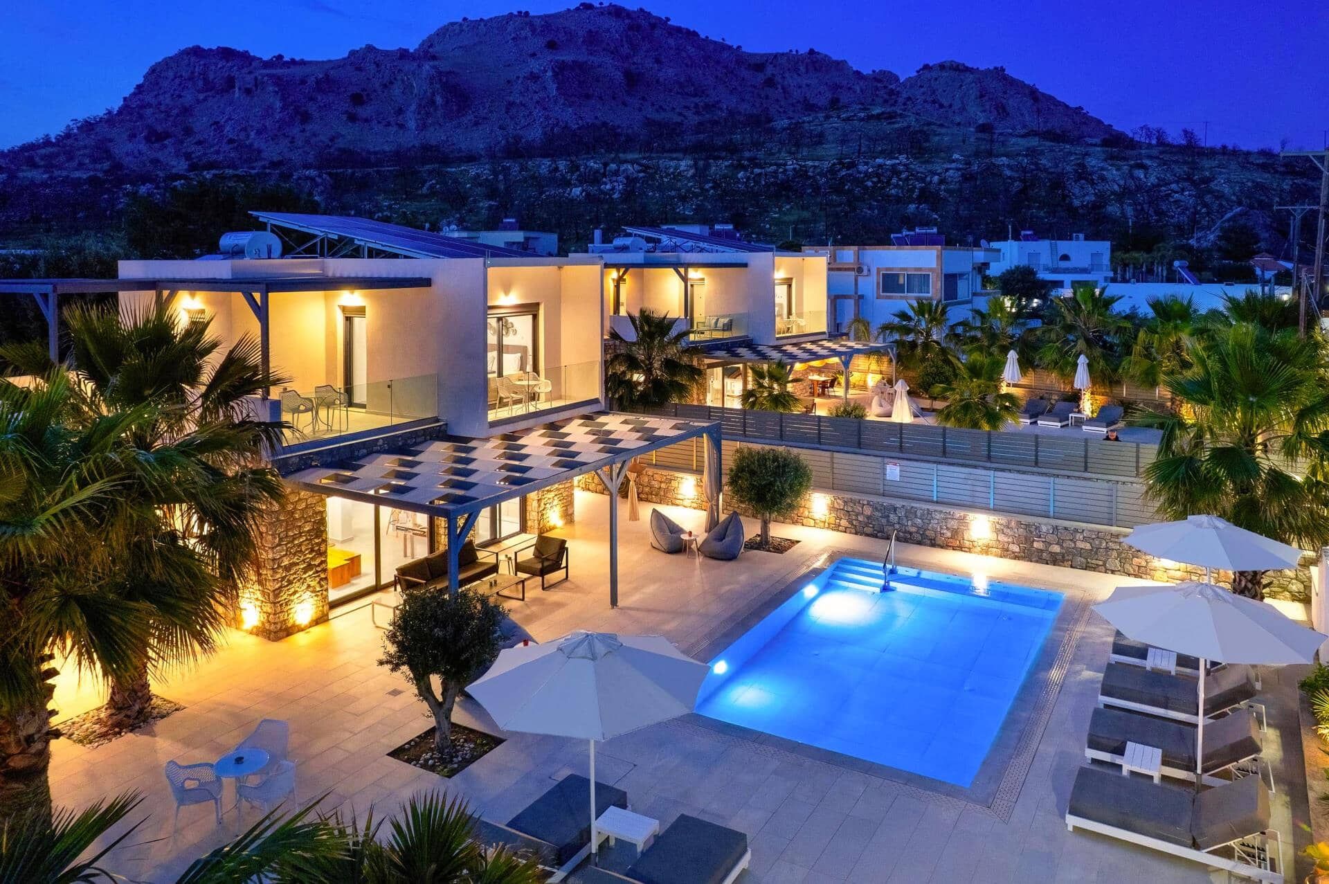 A modern resort with a swimming pool, outdoor seating, and a mountainous backdrop.