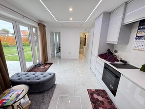 A modern kitchen with white cabinets, a black dishwasher, and a calendar on the wall. - Self-contained Independent beautiful apt (Northolt)
