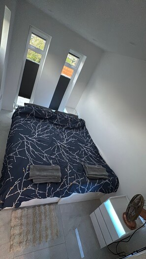 A bedroom with a bed, two windows, and a fan. - Self-contained Independent beautiful apt (Northolt)