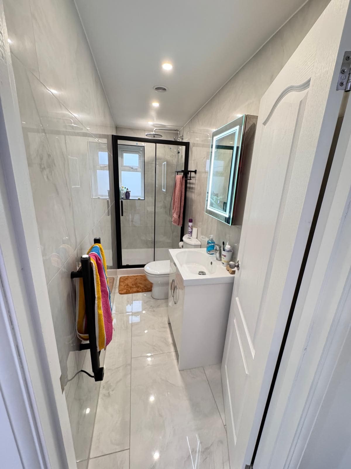 A modern bathroom with a glass shower enclosure, a white sink, and a mirror above the sink.