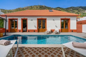 A two-story building with a swimming pool, outdoor seating, and a view of hills. - Villa Casa da Tia by Villa Plus (Machico)