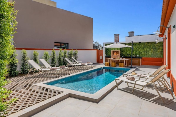 Una piscina amb gandules i una zona de barbacoa.