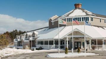 A hotel with a large entrance, multiple flags, and a snow-covered roof.