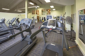 Een fitnessruimte met loopbanden, hometrainers en een roeimachine.