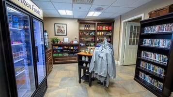 Interno di un negozio di alimentari con prodotti surgelati, un'asta per abiti e una libreria.